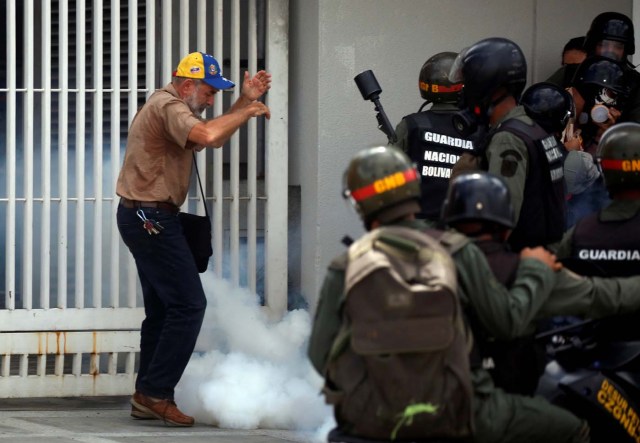 A man stands amidst tear gas smoke as members of the security forces approach him during a rally against Venezuelan President Nicolas Maduro's government in Caracas, Venezuela, July 6, 2017. REUTERS/Carlos Garcia Rawlins