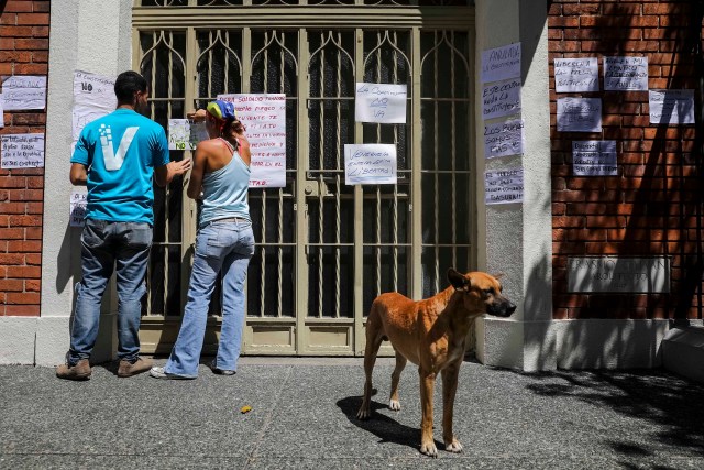 CAR04. CARACAS (VENEZUELA), 24/07/2017.- Una pareja pega carteles en rechazo a la Asamblea Constituyente hoy, lunes 24 de julio de 2017, en un colegio electoral de Caracas (Venezuela). Venezuela inicia hoy la semana decisiva para la elección de la Asamblea Nacional Constituyente convocada por el presidente, Nicolás Maduro, con los oficialistas entrando en la recta final de su campaña en medio de protestas y llamados a paro de los opositores en rechazo a esos comicios. EFE/Miguel Gutiérrez