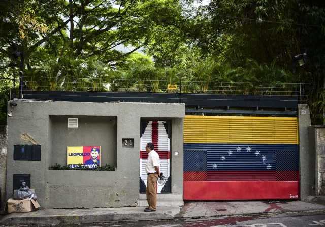 A journalist stands outside the house of Venezuelan opposition leader Leopoldo Lopez in Caracas on August 1, 2017 just hours after he was taken away from his home by the intelligence service. The Venezuelan intelligence service arrested opposition leaders Leopoldo Lopez and Antonio Ledezma overnight Monday, relatives said, a day after a vote to choose a much-condemned assembly that supersedes parliament. Lopez and Ledezma were both already under house arrest when they were picked up by the intelligence service known by its in acronym Sebin, the wife of Lopez and children of Ledezma said separately. / AFP PHOTO / Ronaldo SCHEMIDT