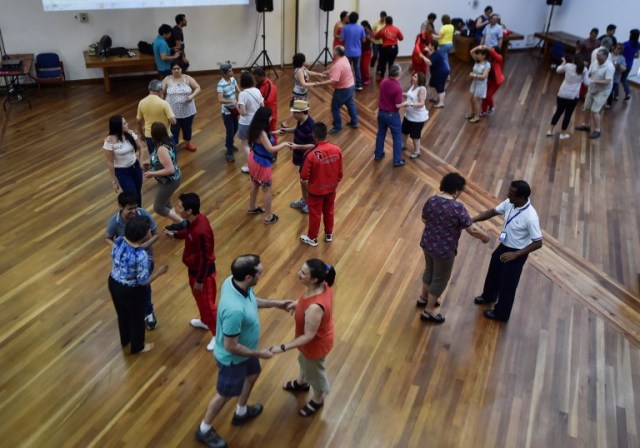 Visually impaired people attend a salsa dance class in Cali, Colombia, on August 13, 2017, during the eighth version of the "Tifloencuentro". 69 people with visual impairment from eight countries of Latin America and Europe take part in the "Tifloencuentro", a tourism event in which blind and people with low vision meet in a cultural exchange of life experiences. / AFP PHOTO / LUIS ROBAYO / TO GO WITH AFP STORY