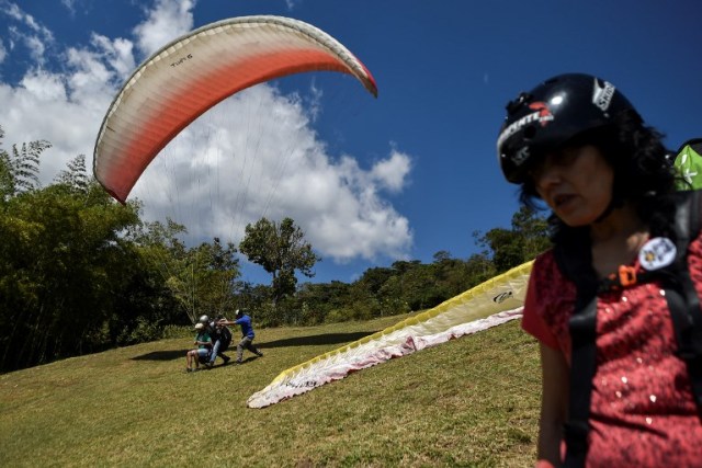 A visually impaired man takes off with a paraglider in a rural area of Palmira, Colombia, during the eighth version of Tifloencuentro on August 14, 2017. 69 people with visual impairment from eight countries of Latin America and Europe take part in the "Tifloencuentro", a tourism event in which blind and people with low vision meet in a cultural exchange of life experiences. / AFP PHOTO / LUIS ROBAYO