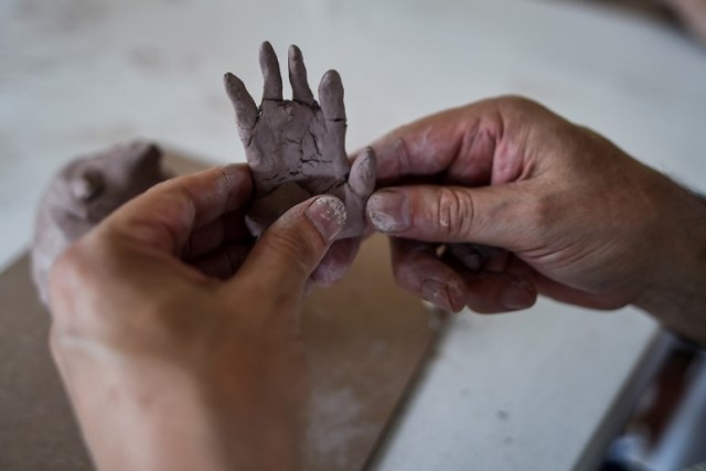 A visually impaired man models a clay sculpture on August 14, 2017, in rural area of Palmira, Colombia, during the eighth version of Tifloencuentro. 69 people with visual impairment from eight countries of Latin America and Europe take part in the "Tifloencuentro", a tourism event in which blind and people with low vision meet in a cultural exchange of life experiences. / AFP PHOTO / LUIS ROBAYO