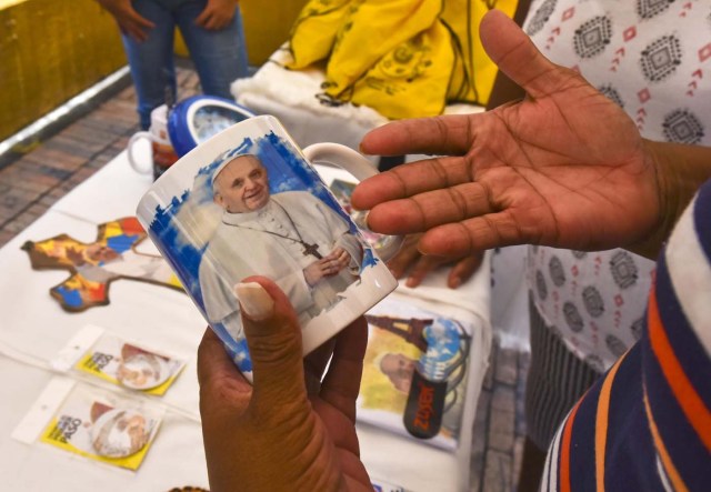 A woman buys a cup with the image of Pope Francis in Villavicencio, Meta, Colombia - where he will give mass during his upcoming visit to Colombia - on August 28, 2017. Pope Francis will make a special four-day visit to Colombia, from September 6-11, to add his weight to the process of reconciliation between the government and the FARC. / AFP PHOTO / LUIS ACOSTA