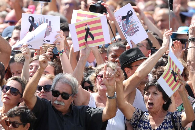 People hold banners as they observe a minute of silence in Placa de Catalunya, a day after a van crashed into pedestrians at Las Ramblas in Barcelona, Spain August 18, 2017. REUTERS/Sergio Perez