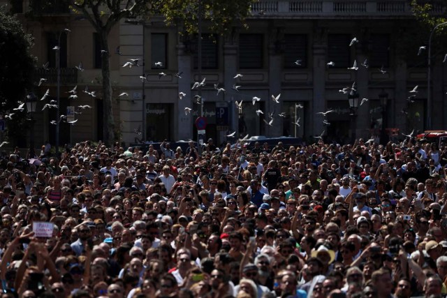 Doves fly over people gathered to observe a minute of silence at Placa de Catalunya, a day after a van crashed into pedestrians at Las Ramblas in Barcelona, Spain August 18, 2017. REUTERS/Susana Vera