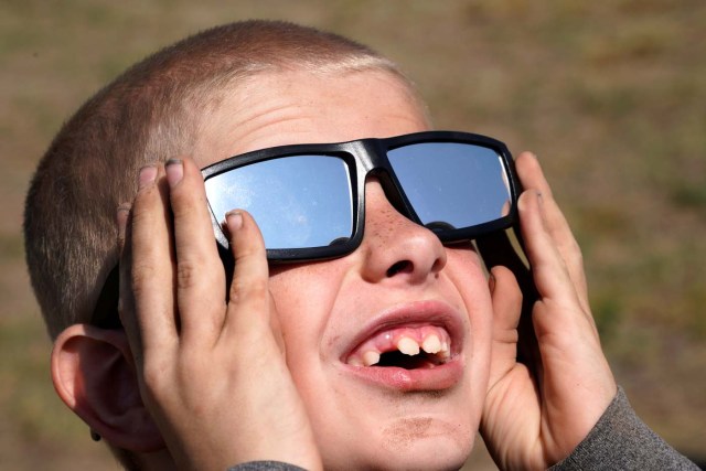 Cooper Jackson tries out his new solar glasses in a designated eclipse viewing area in a campground near Guernsey, Wyoming, U.S., August 20, 2017. REUTERS/Rick Wilking