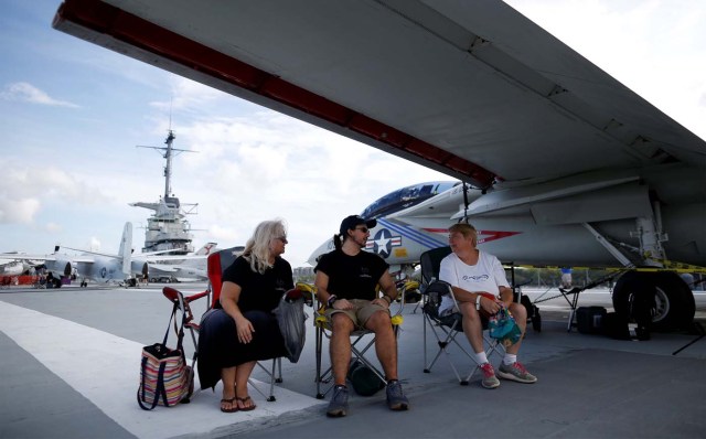 Candace Marz (Left) and her son Gabriel Marz, of Aynor, South Carolina and Jean Garrett of Pequea, Pennsylvania, wait under the wing of a F-14A on the Naval museum ship U.S.S. Yorktown before festivities start for the Great American Eclipse in Mount Pleasant, South Carolina, U.S. August 21, 2017. Location coordinates for this image are 32º47'26" N 79º54'31" W. REUTERS/Randall Hill