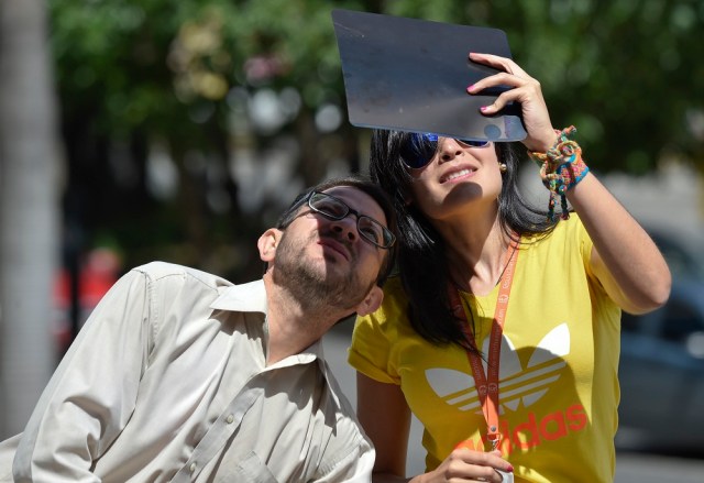 People watch through special filters the solar eclipse in Caracas, on August 21, 2017. / AFP PHOTO / JUAN BARRETO