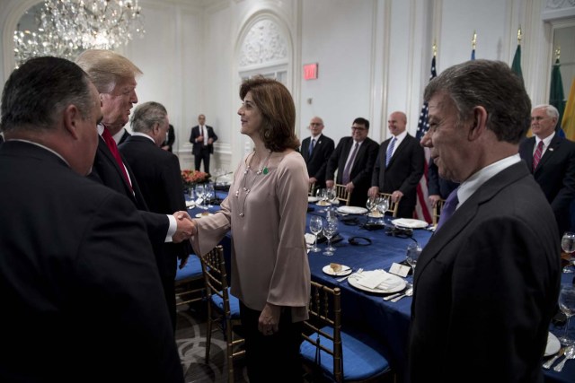 Colombia's President Juan Manuel Santos (R) watches as US President Donald Trump greets Colombian Foreign Minister Maria Angela Holguin Cuellar (2nd R) before a dinner with Latin American and US leaders at the Palace Hotel during the 72nd session of the United Nations General Assembly September 18, 2017 in New York City. / AFP PHOTO / Brendan Smialowski