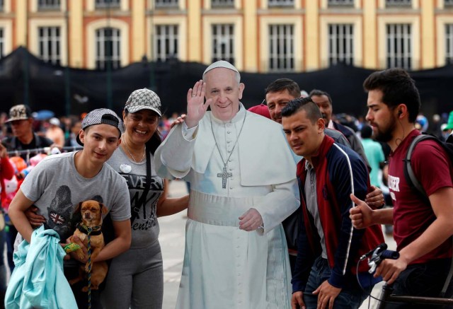 People pose beside a poster with an image of Pope Francis outside the Narino Palace in Bogota, Colombia September 3, 2017. REUTERS/Henry Romero