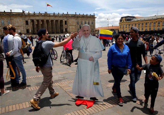 People walk past a poster with a image of Pope Francis outside the Narino Palace in Bogota, Colombia September 3, 2017. REUTERS/Henry Romero