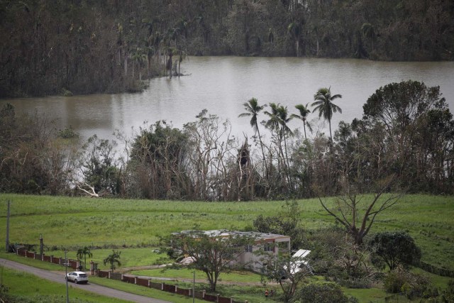 A car drives past a damaged house next to the Guajataca lake after the area was hit by Hurricane Maria in Guajataca, Puerto Rico September 23, 2017. REUTERS/Carlos Garcia Rawlins