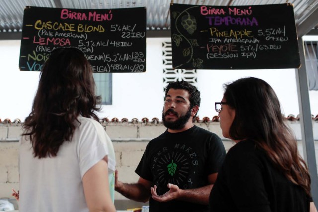 Victor Querales (C), one of the owners of Social Club brewery, explains to customers the variety of craft beers on offer in a beer garden at the garage of his brewery in Caracas, Venezuela September 15, 2017. Picture taken September 15, 2017. REUTERS/Marco Bello