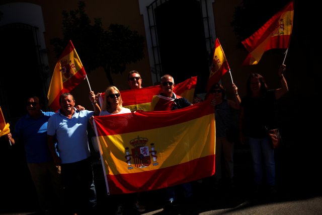 Four Spanish Civil Guard officers and their wives hold up Spanish flags during a gathering in support of Spain's National Police and Civil Guard officers working in Catalonia, outside a Spanish local police headquarters in Malaga, Spain October 6, 2017. REUTERS/Jon Nazca