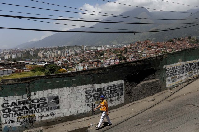 A resident walks past a campaign graffiti of opposition candidate for the government of Miranda Carlos Ocariz ahead the governors elections, which will be held on October 15, in Caracas, Venezuela, October 13, 2017.  REUTERS/Ricardo Moraes