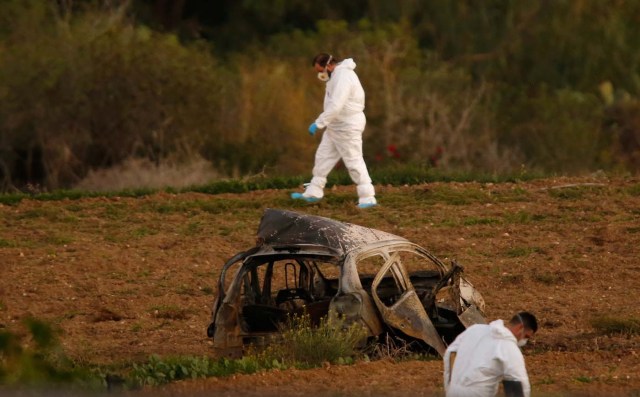 Forensic experts walk in a field after a powerful bomb blew up a car (Foreground) and killed investigative journalist Daphne Caruana Galizia in Bidnija, Malta, October 16, 2017. REUTERS/Darrin Zammit Lupi     TPX IMAGES OF THE DAY