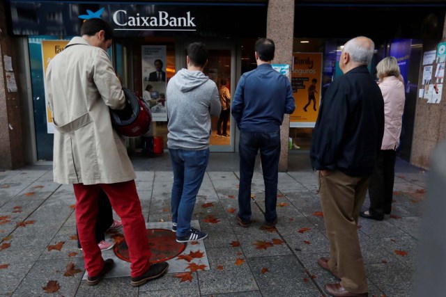 People line up at a cashpoint of La Caixa bank branch to withdraw money as part of an action to protest the transfer of the bank's headquarters out of Barcelona, Spain, October 20, 2017. REUTERS/Gonzalo Fuentes