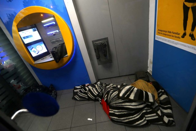 A man sleeps by a Caixa Bank ATM at their branch office, on the day of a protest against the transfer of the bank's headquarters out of Barcelona, Spain, October 20, 2017. REUTERS/Ivan Alvarado