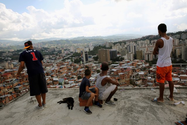 Cuatro muchachos miran hacia adelante como uno vuela una cometa sobre casas en el barrio pobre de Caracas, Venezuela, 29 de agosto de 2017. Foto tomada el 29 de agosto de 2017. Para coincidir con la característica VENEZUELA-NIÑOS / REUTERS / Andres Martínez Casares