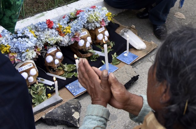 An Aymara woman prays next to her "natitas" (snub-nosed) human skulls during the annual traditional ritual at the Central Cemetery of La Paz on November 8, 2017. The "natitas" are meant to protect their owners, who keep them at home all year long and bring them to the cemetery chapels every November 8 to perform rituals which end up in a traditional party. / AFP PHOTO / Aizar RALDES