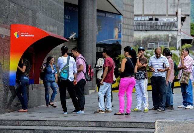 People queue to withdraw money from an ATM in Caracas on November 14, 2017. Venezuela has been declared in "selective default" by Standard and Poor's after failing to make interest payments on bond issues as it tries to refinance its $150 billion foreign debt. / AFP PHOTO / Federico PARRA