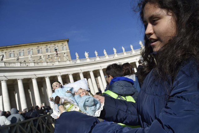 A little girl holds figurines of Baby Jesus in direction of Pope Francis during the traditional benediction of the figurines as part of the Sunday Angelus prayer before Christmas, on December 17, 2017 at St Peter's square in Vatican.  / AFP PHOTO / Andreas SOLARO