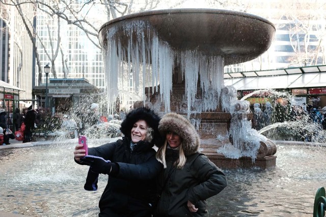 NEW YORK, NY - DECEMBER 27: Two women take a selfie photo in front of a frozen fountain in Bryant Park on a frigid day in Manhattan on December 27, 2017 in New York City. Dangerously low temperatures and wind chills the central and eastern United States are making outdoor activity difficult for many Americans. Little relief from the below normal temperatures is expected the first week of the New Year.   Spencer Platt/Getty Images/AFP