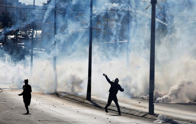 A Palestinian protester hurls stones as tear gas is fired by Israeli troops during clashes as Palestinians call for a "day of rage" in response to U.S. President Donald Trump's recognition of Jerusalem as Israel's capital, in the West Bank city of Bethlehem December 8, 2017. REUTERS/Mussa Qawasma