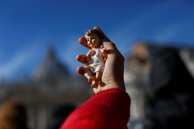 A child holds a statue of baby Jesus as Pope Francis leads his Sunday Angelus prayer, on the day of his birthday, in Saint Peter's square at the Vatican December 17, 2017. REUTERS/Tony Gentile