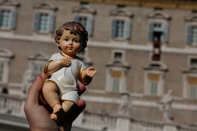 A man holds a statue of baby Jesus as Pope Francis leads his Sunday Angelus prayer, on the day of his birthday, in Saint Peter's square at the Vatican December 17, 2017. REUTERS/Tony Gentile