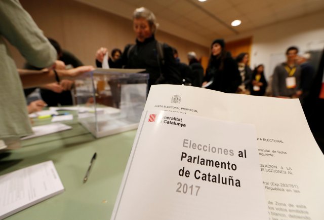 A voter casts their ballot as others wait to vote in Catalonia's regional elections at a polling station in Sant Cugat del Valles, Spain December 21, 2017. REUTERS/Eric Gaillard
