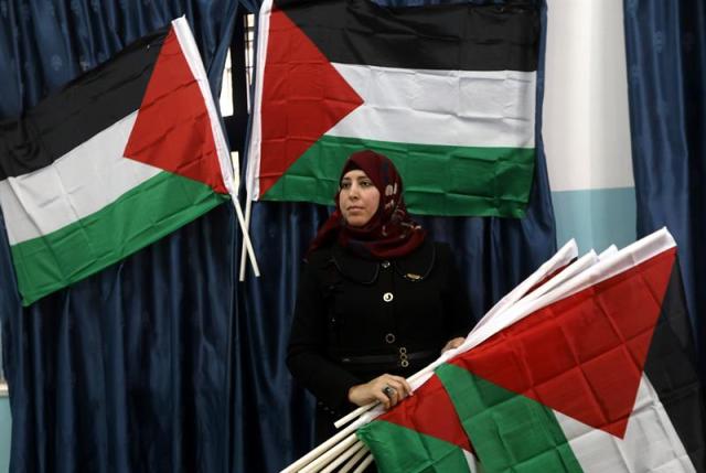 Una mujer lleva varias banderas palestinas durante una protesta convocada en la ciudad cisjordana de Ramala, hoy, 6 de diciembre de 2017. Las fuerzas de seguridad israelíes se preparan para un posible incremento de la violencia, tras el esperado reconocimiento hoy del presidente de EEUU, Donald Trump, de Jerusalén como capital de Israel y la promesa de trasladar su embajada de Tel Aviv a la ciudad santa. EFE/ Alaa Badarneh