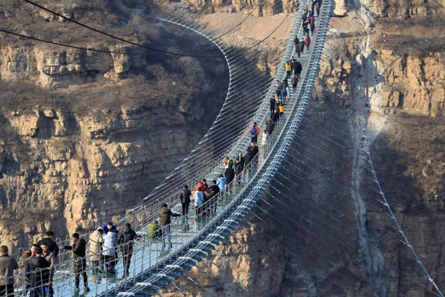 Visitors walk on the newly opened 488-metre-long glass suspension bridge at Hongyagu attraction in Pingshan, Hebei province, China December 26, 2017. Picture taken December 26, 2017. Zhang Haiqiang via REUTERS ATTENTION EDITORS - THIS IMAGE WAS PROVIDED BY A THIRD PARTY. CHINA OUT.