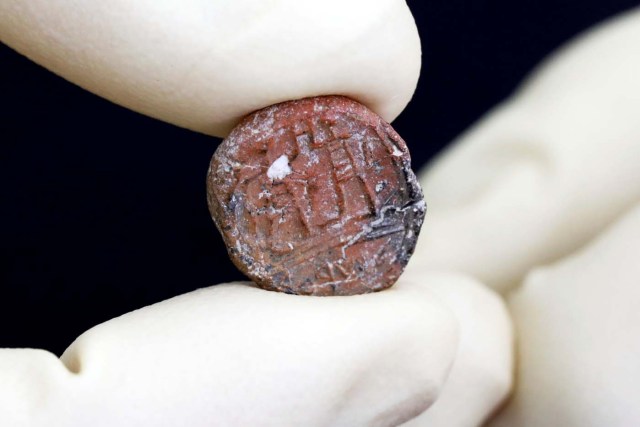 A conservator shows a 2,700-year-old clay seal impression which archaeologists from the Israel Antiquities Authority say belonged to a biblical governor of Jerusalem and was unearthed in excavations in the Western Wall plaza in Jerusalem's Old City January 1, 2018. REUTERS/Nir Elias