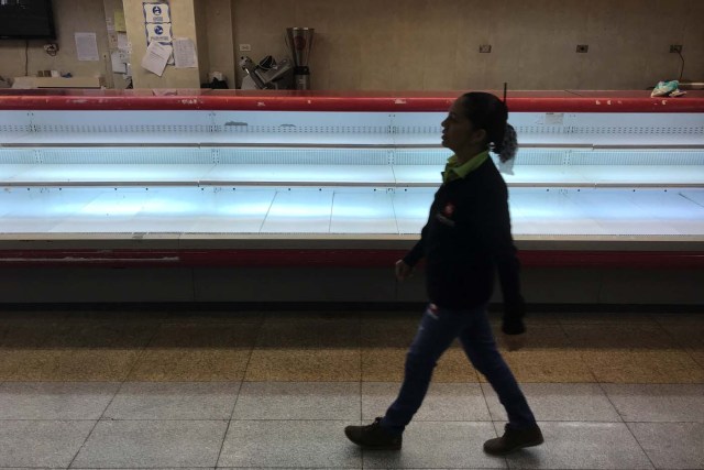 A woman walks past an empty refrigerator at a supermarket in Caracas, Venezuela January 9, 2018. REUTERS/Marco Bello