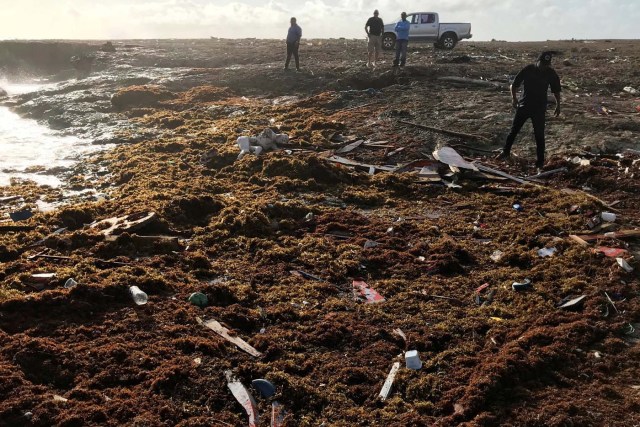 ATTENTION EDITORS - VISUALS COVERAGE OF SCENES OF INJURY OR DEATH   A member of the coast guard (R) walks close to the body of a person who was found at the shore, near Willemstad, Curacao January 12, 2018. REUTERS/Umpi Welvaart   TEMPLATE OUT