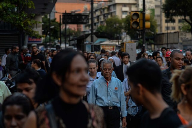 People walk along a street during a partial power cut in Caracas on February 6, 2018. / AFP PHOTO / FEDERICO PARRA