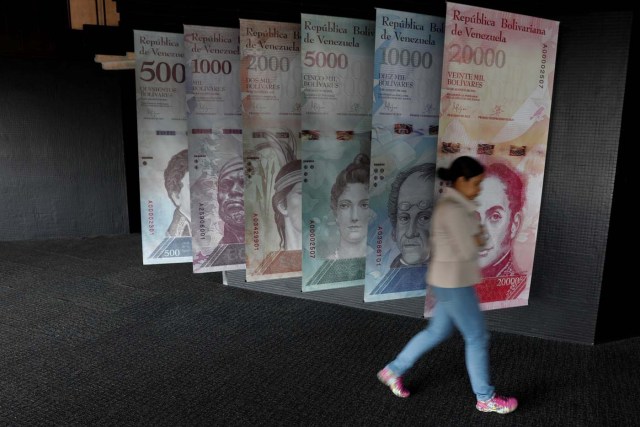 A woman walks by banners of Venezuelan bolivar notes displayed at the Venezuelan Central Bank building in Caracas, Venezuela, January 31, 2018. REUTERS/Marco Bello