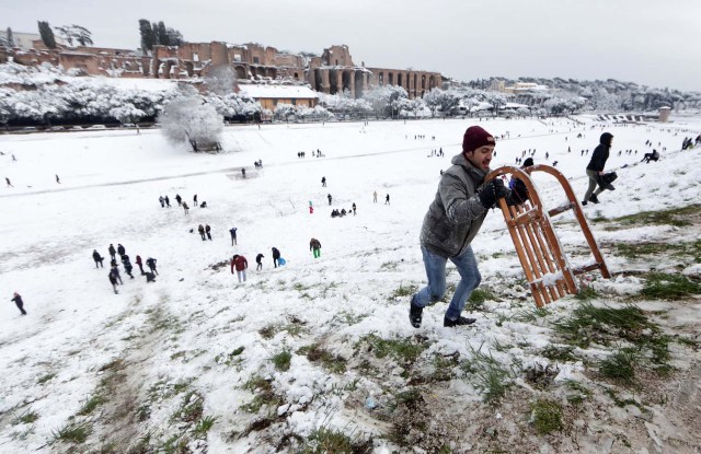 A man carries a sledge during a heavy snowfall, at the Circus Maximus, in Rome, Italy February 26, 2018. REUTERS/Yara Nardi