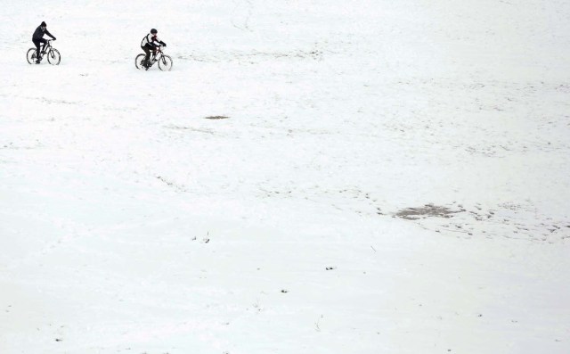 People cycle during a heavy snowfall at the Circus Maximus in Rome, Italy February 26, 2018. REUTERS/Yara Nardi