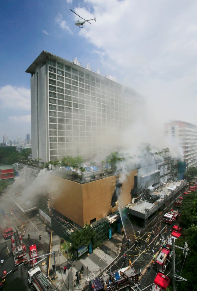 A helicopter flies over the building to rescue hotel guests and workers who were trapped after a fire engulfed the Manila Pavilon hotel in Metro Manila, Philippines March 18, 2018. REUTERS/Romeo Ranoco