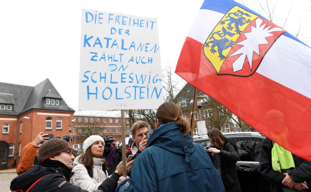 A protestor holda a flag of Schleswig Holstein and a placard reading "The fredom of the Catalans also counts in Schleswig Holstein" in front of the prison in Neumuenster, Germany, March 26, 2018, after former Catalan leader Carles Puigdemont was detained on Sunday in Germany.     REUTERS/Fabian Bimmer