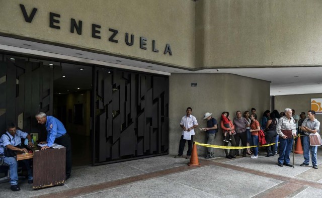 Venezuelans queue at the Chilean consulate in Caracas, to apply for a "Democratic Responsibility Visa" on April 16, 2018. Chilean President Sebastian Pinera announced on April 8 that Chile would ease visa regulations for Venezuelans fleeing the political crisis. In light of the "grave democratic crisis" gripping Venezuela, Pinera said he was creating a so-called visa of "democratic responsibility" which Venezuelan citizens could obtain through the Chilean embassy in Caracas. / AFP PHOTO / Luis ROBAYO