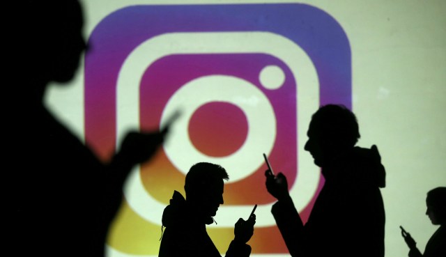 REFILE - CLARIFYING CAPTION Silhouettes of mobile users are seen next to a screen projection of Instagram logo in this picture illustration taken March 28, 2018.  REUTERS/Dado Ruvic/Illustration