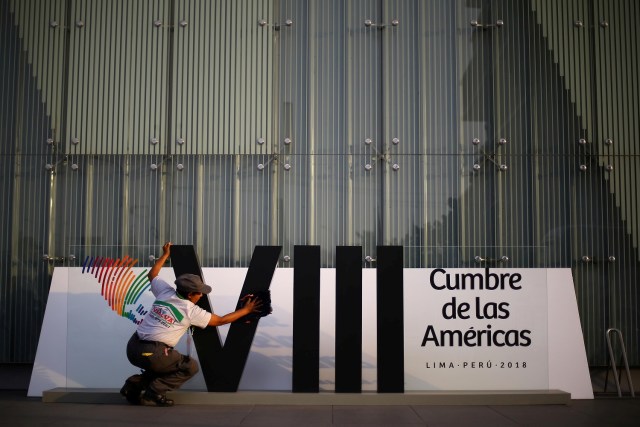 Una mujer limpia la insignia de la VIII Cumbre de las América antes de su inicio en Lima, Perú, 10 de abril de 2018. REUTERS/Ivan Alvarado - RC11B161FBE0