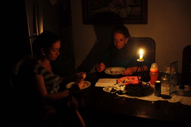 Carmenza Herrera (C) and her family use a candle to illuminate the table while they dine, during a blackout in San Cristobal, Venezuela, April 19, 2018. Picture taken April 19, 2018. REUTERS/Carlos Eduardo Ramirez