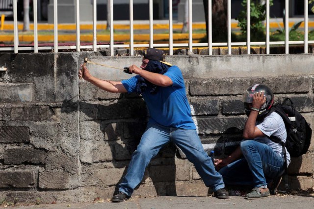 A demonstrator uses a slingshot to hurl stones against riot police during a protest over a controversial reform to the pension plans of the Nicaraguan Social Security Institute (INSS) in Managua, Nicaragua April 20, 2018. REUTERS/Oswaldo Rivas