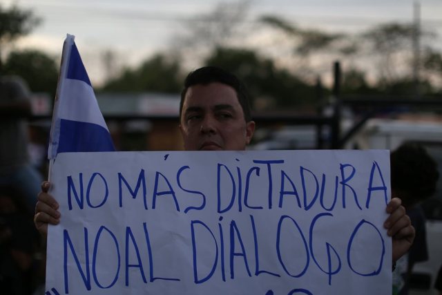 A man holds a poster that reads "no more dictatorship, no to dialog" during a memorial for journalist Angel Gahona in Managua, Nicaragua on April 25, 2018. REUTERS/Jose Cabezas