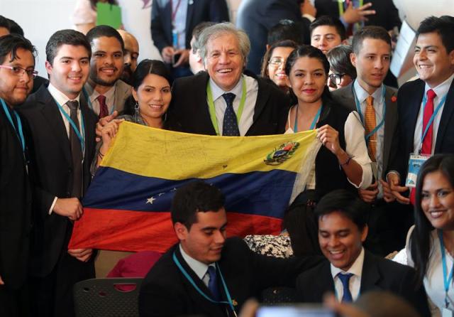 El secretario general de la Organización de Estados Americanos (OEA), Luis Almagro (c), posa para una foto con un grupo de jóvenes que sostienen una bandera venezolana hoy, miércoles 11 de abril de 2018, durante el Foro de los Jóvenes, una de las reuniones preparatorias para la Cumbre de las Américas, en Lima (Perú). EFE