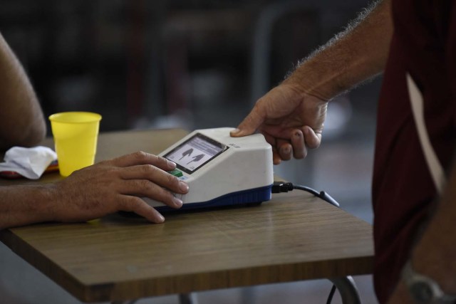 A man puts his finger on a fingerprint scanner after casting his ballot during the presidential elections in Caracas, Venezuela on May 20, 2018 Venezuelans, reeling under a devastating economic crisis, began voting Sunday in an election boycotted by the opposition and condemned by much of the international community but expected to hand deeply unpopular President Nicolas Maduro a new mandate / AFP PHOTO / Carlos Becerra